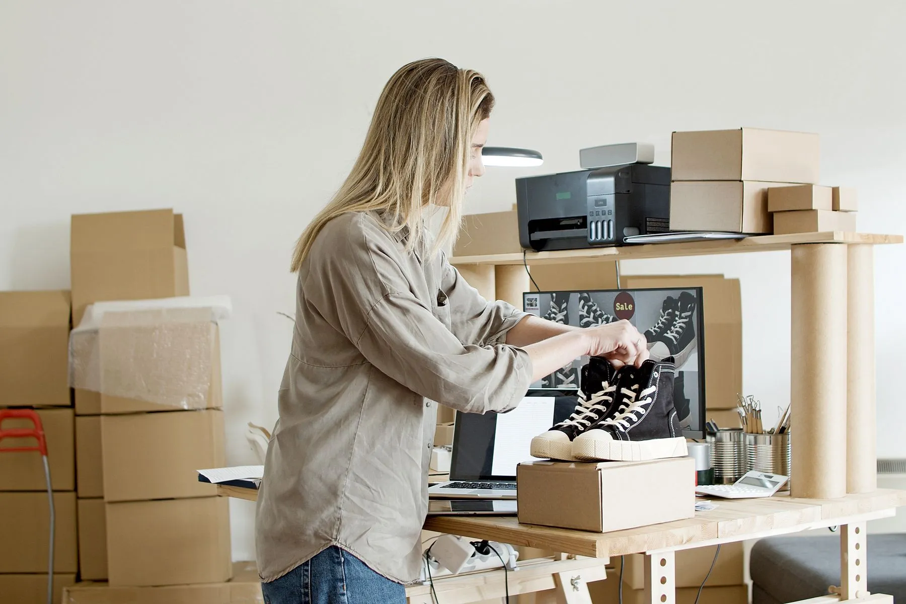 Empreendedora embalando um pedido de loja virtual entre caixas de envio